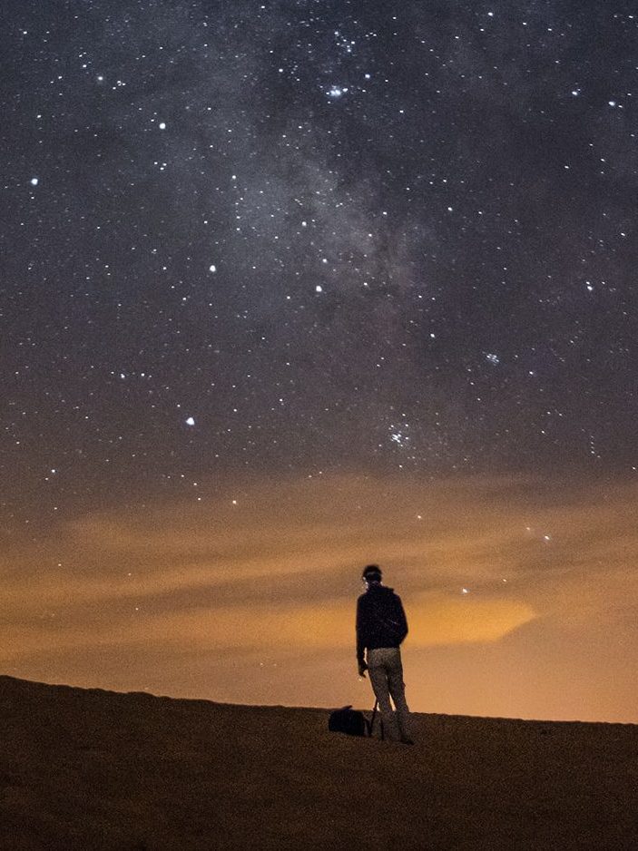 picture of a man on a hill looking at stars in the sky